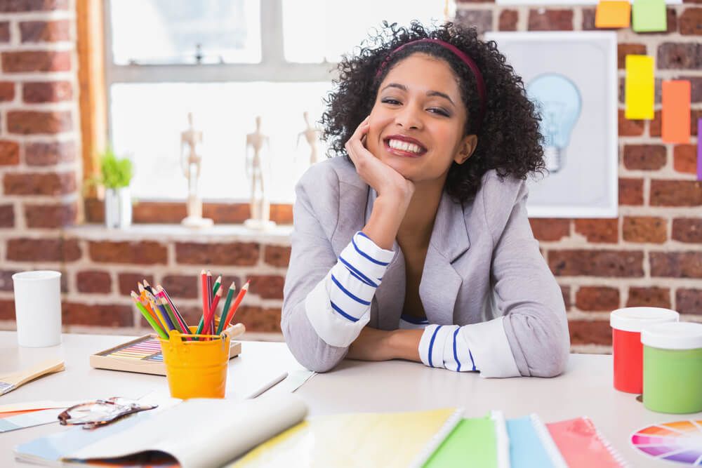 Portrait of smiling female interior designer sitting at office desk