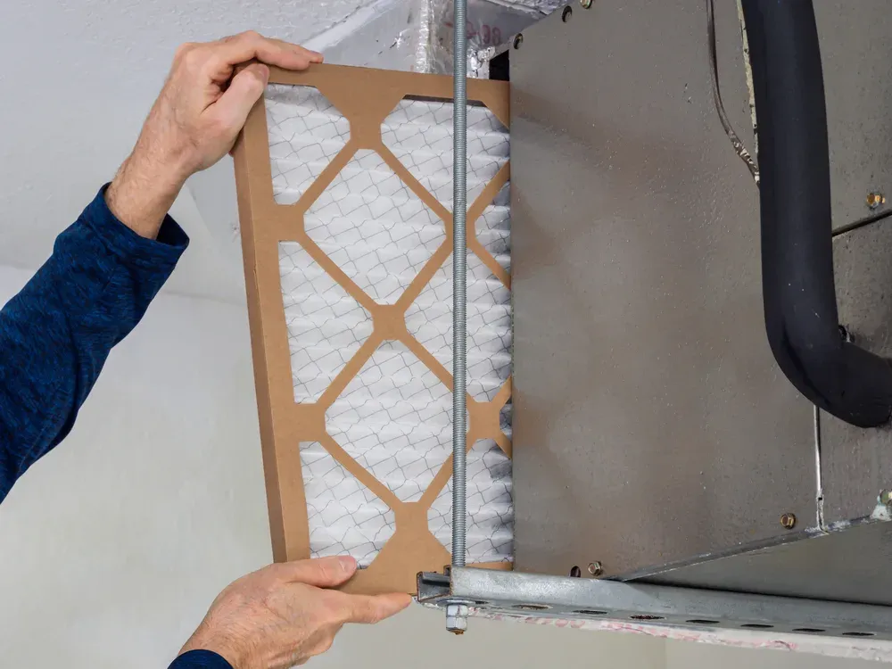HVAC service technician changing indoor air filter 