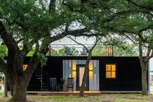 black shipping container home with a deck 